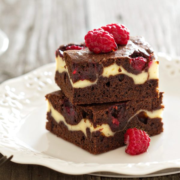 Cheesecake brownies with raspberry stacked on a plate