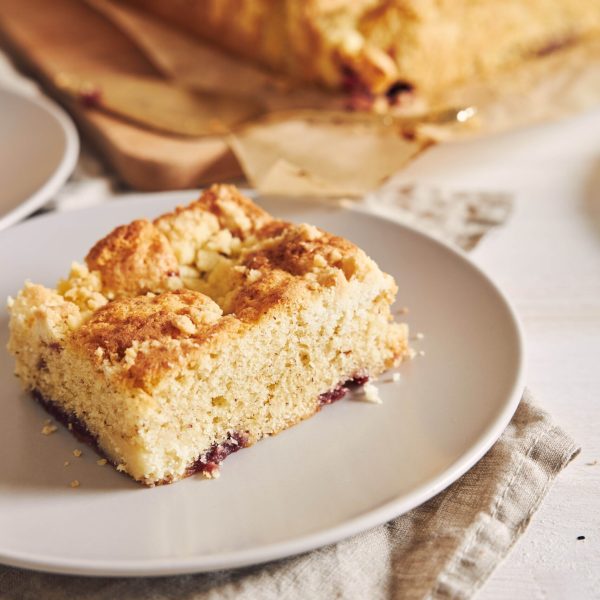 A vertical picture of a piece of delicious Jerry Crumble Sheet cake on a white wood table - perfect background for confectionery shop